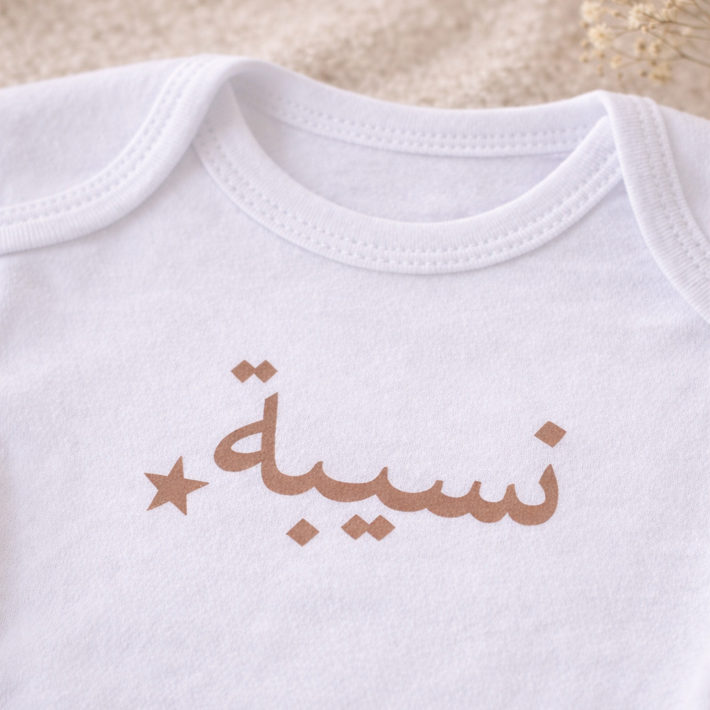Zoom flocage prénom arabe sur body bébé personnalisé, écriture cappuccino avec étoile, rendu lisse vinyle thermocollé sur coton blanc